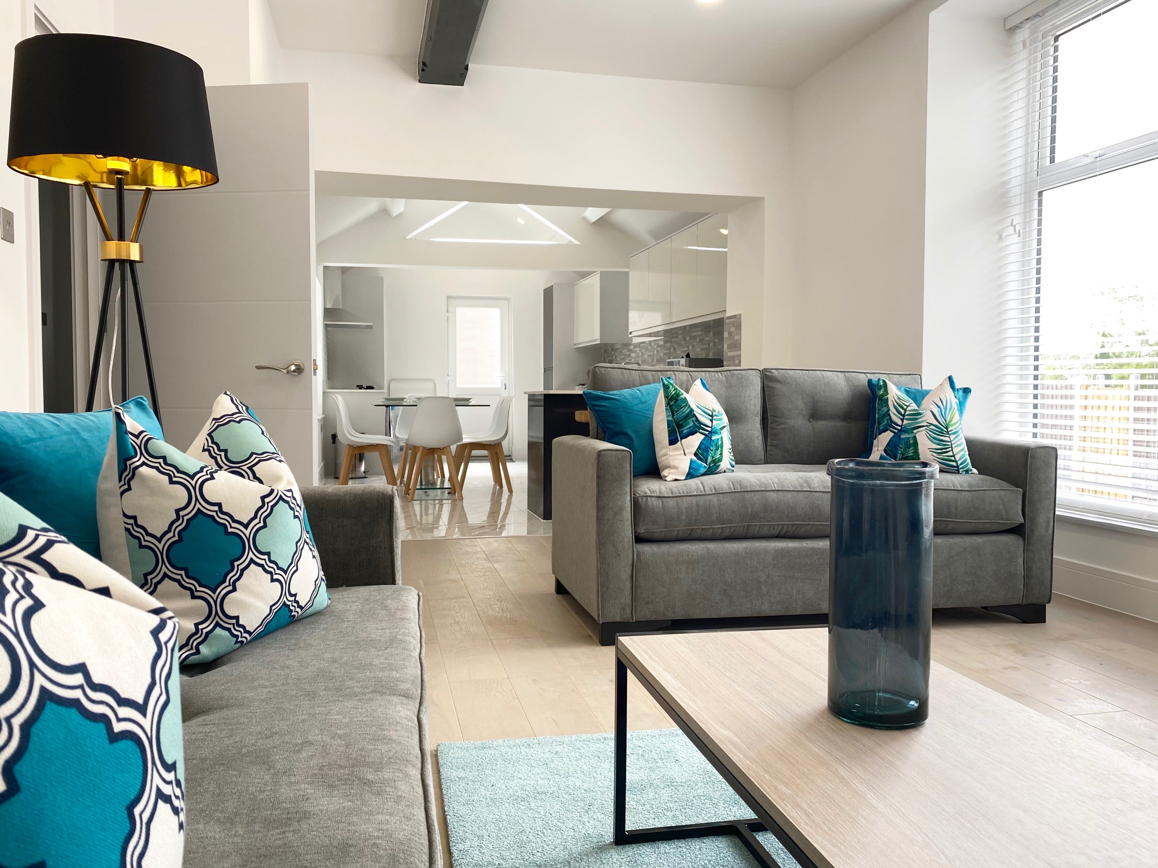 Grey sofas, blue rug, coffee table, black floor lamp and bright blue cushions