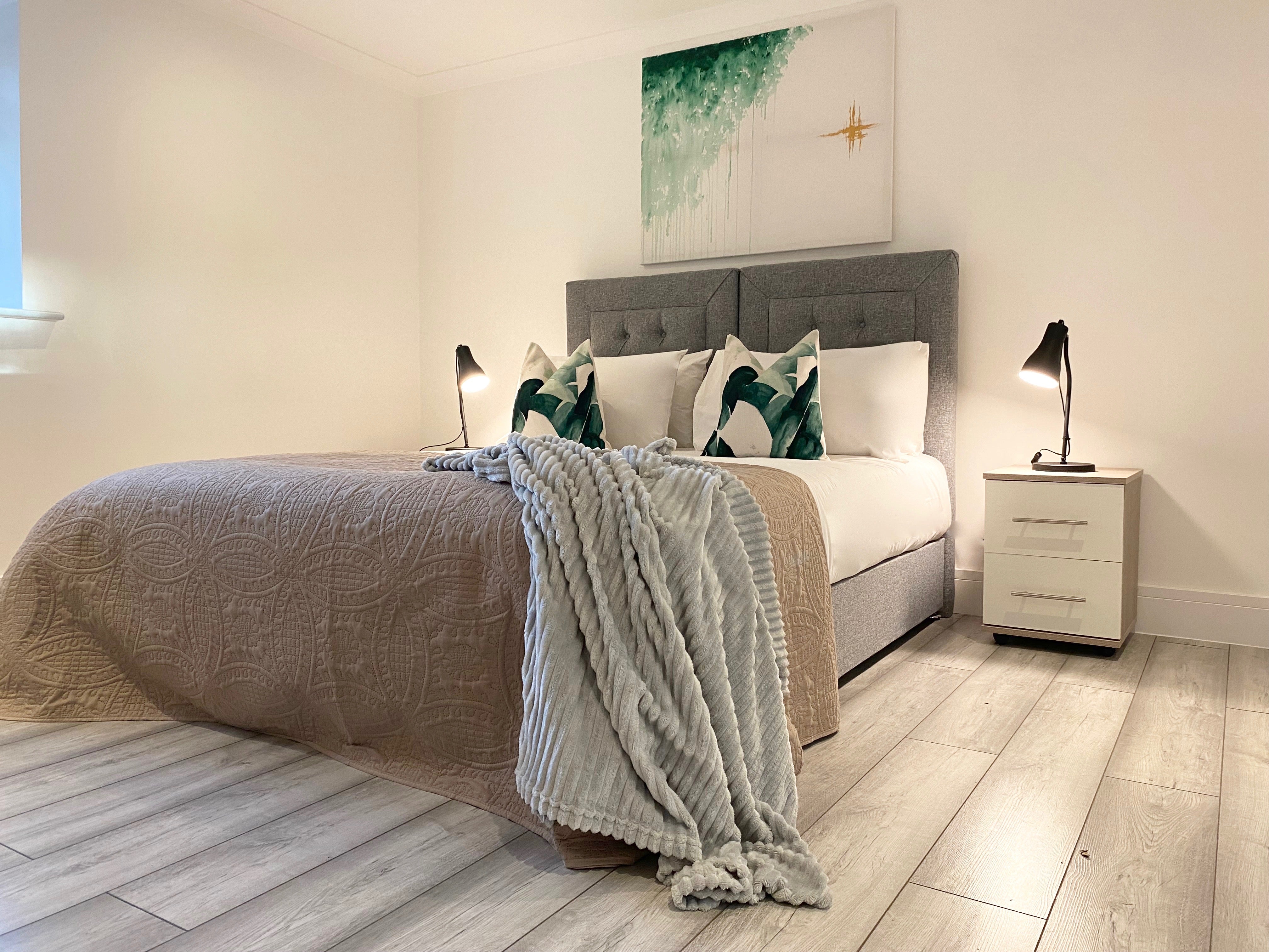 Zip and link bed with green cushions, green artwork and white bedside