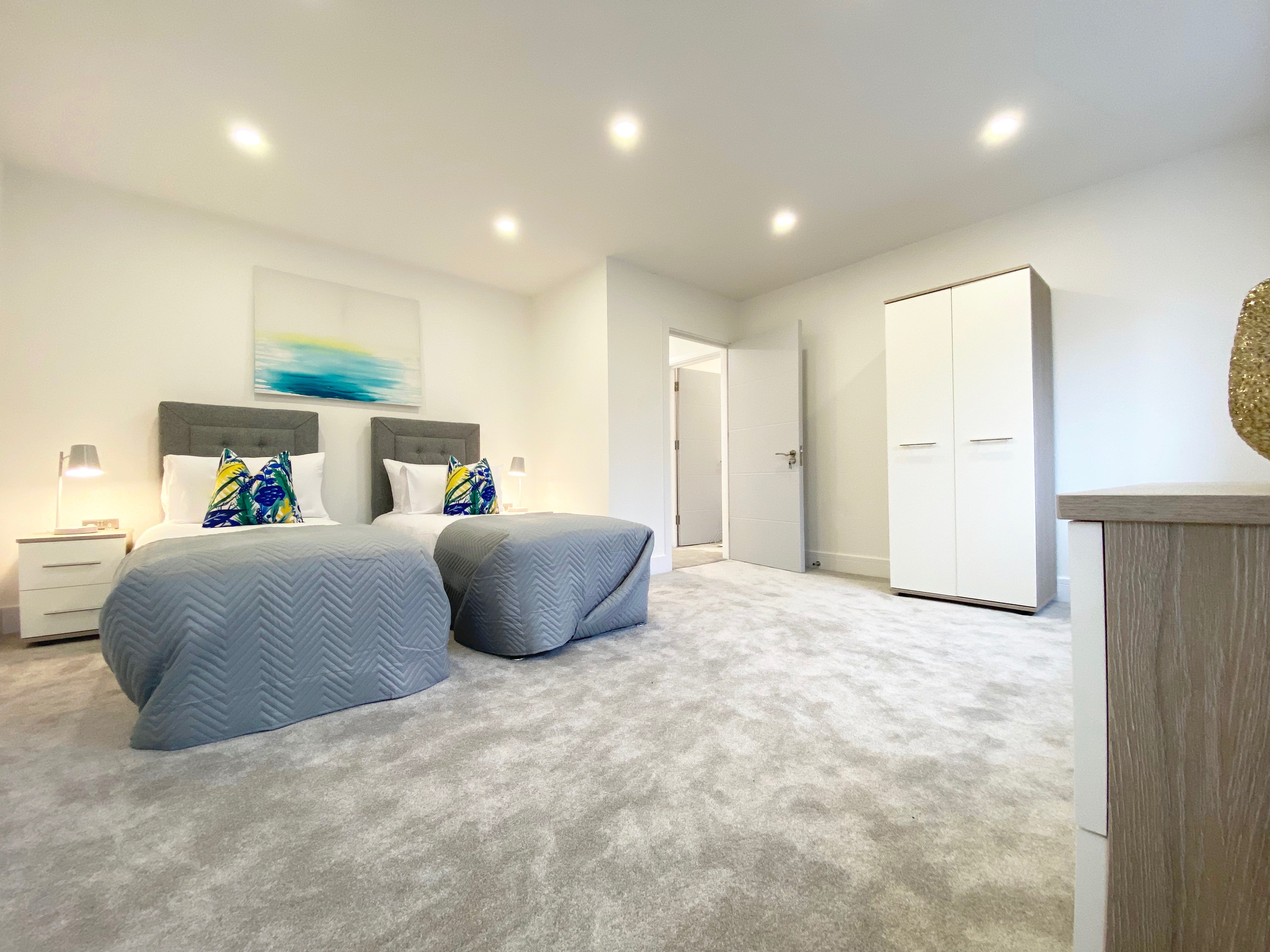 Two single beds with grey bedspread, white wardrobe