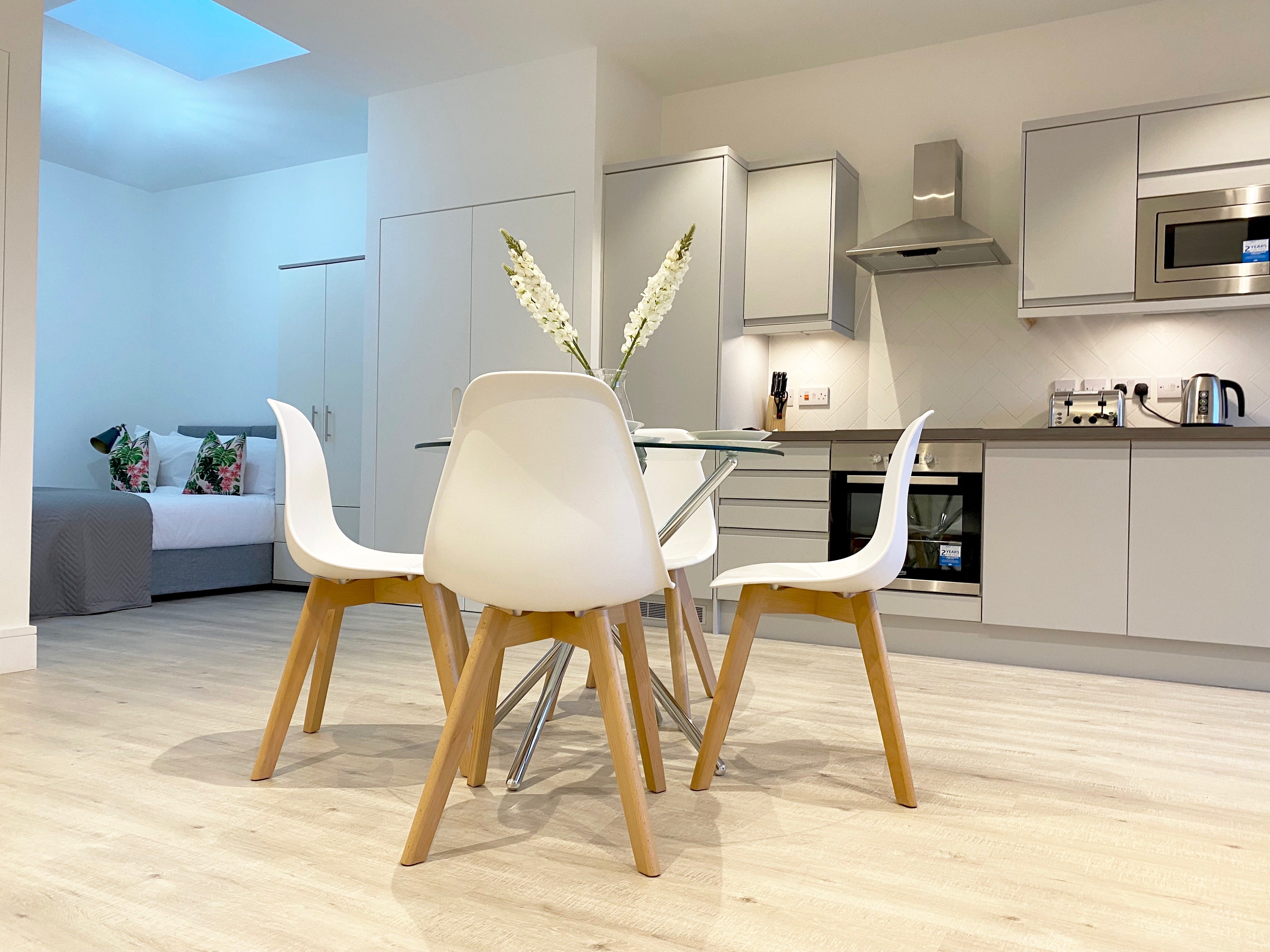 Glass round dining table with white chairs in modern grey kitchen